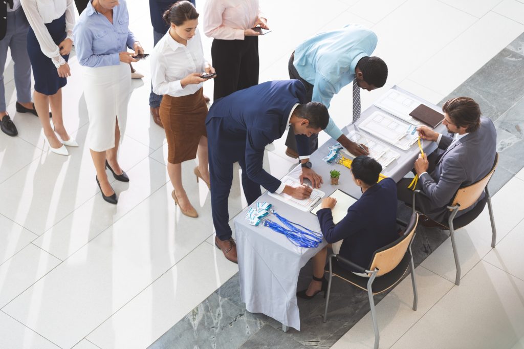Business people checking in at conference registration table in office lobby